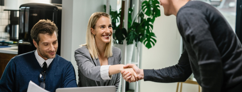 two-financial-advisors-having-meeting-with-young-man-home-female-advisor-is-shaking-hands-with-client-scaled.jpg